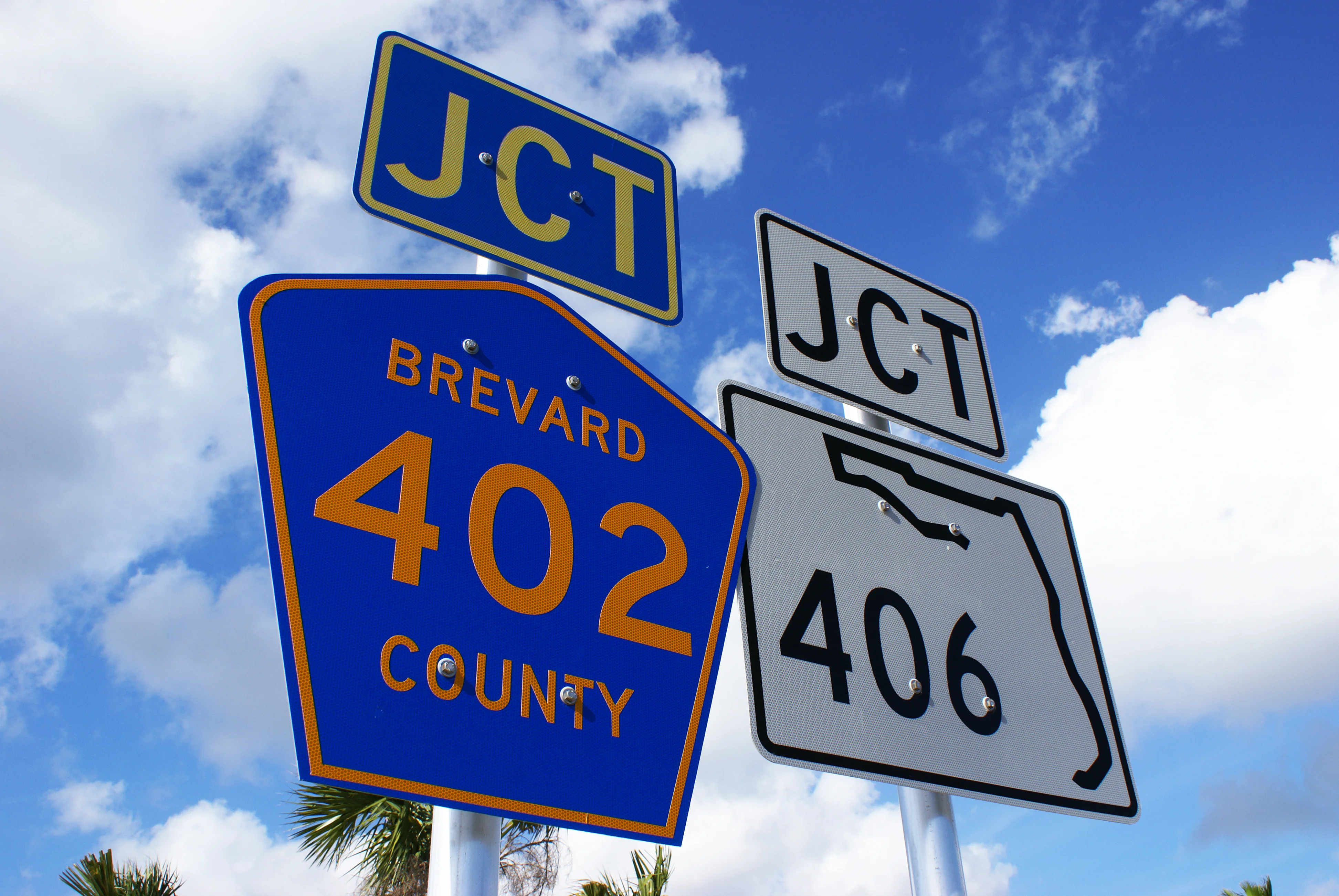 Brevard County road signs at a junction in Florida under a bright blue sky, representing local property management areas served by Osto Property Management.