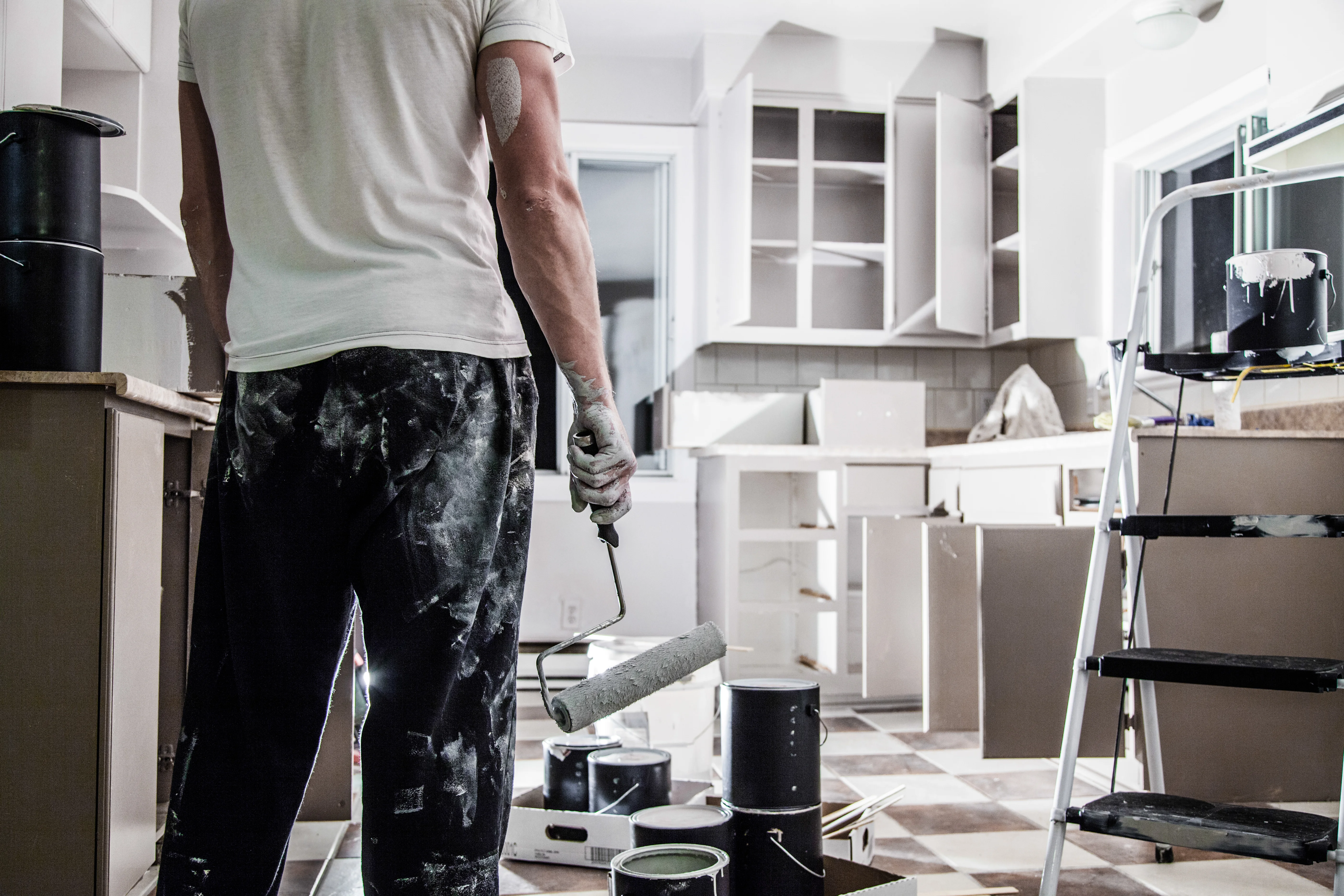 Landlord painting kitchen cabinets during rental property renovation as part of maintenance.