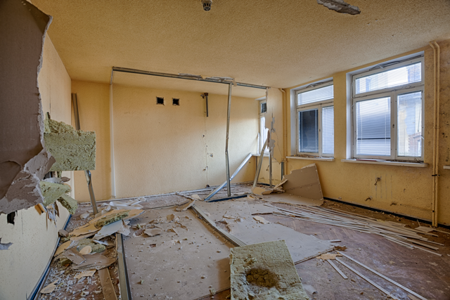 amaged rental property interior with broken walls and debris, showing unsafe living conditions.